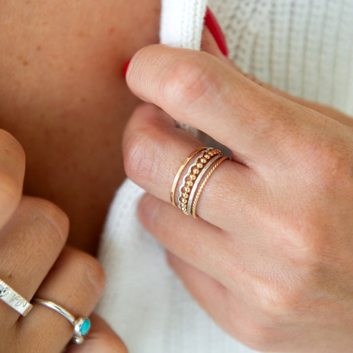 Mixed metal stacking ring set with hammered, beaded, twisted and squiggle rings in sterling silver and 14k gold filled