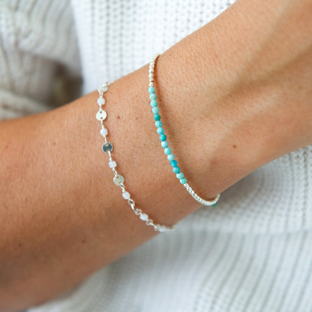 sterling silver stardust bracelet with white moonstone paired with gemstone bracelet in turquoise on wrist