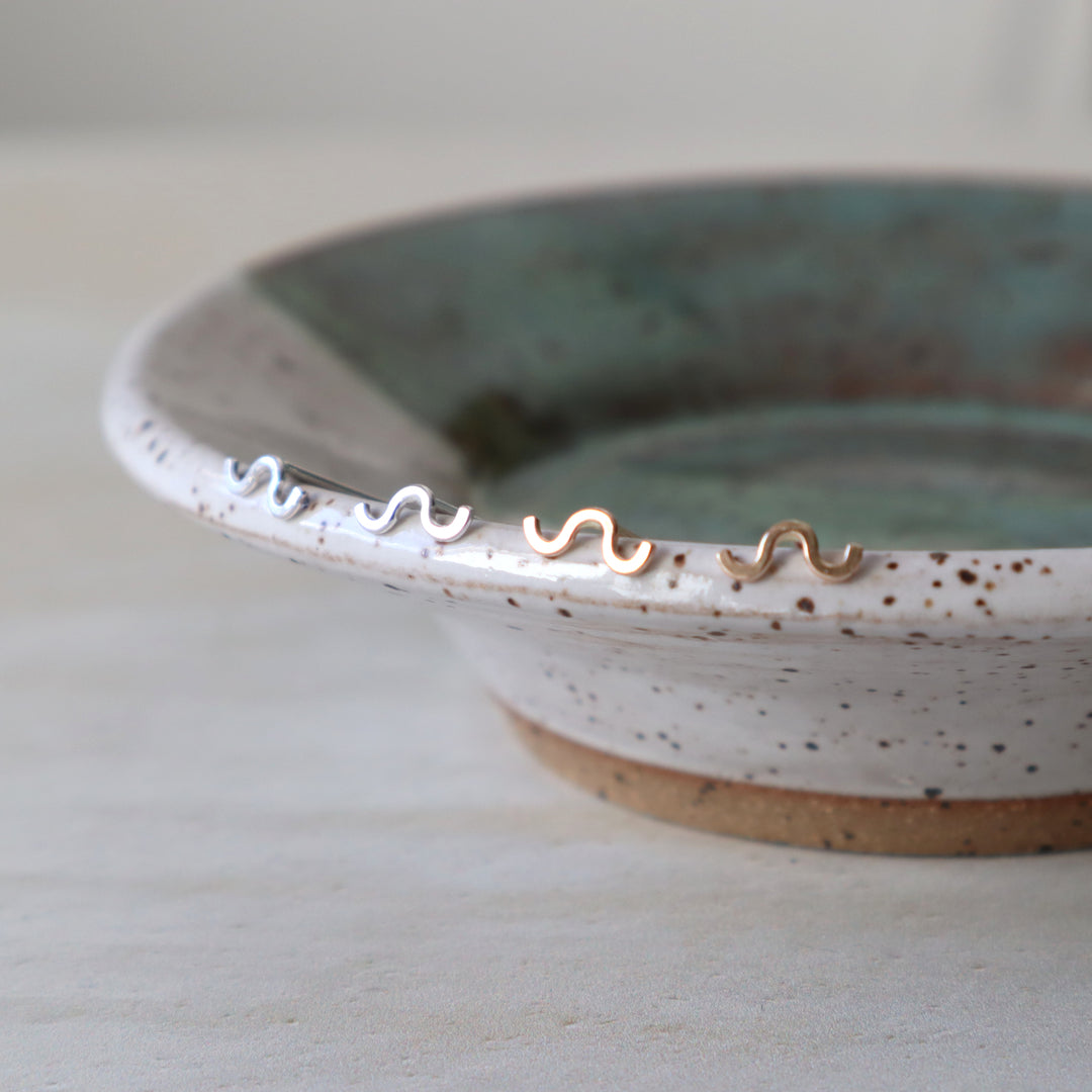 Ceramic dish with squiggle stud earrings on a light background
