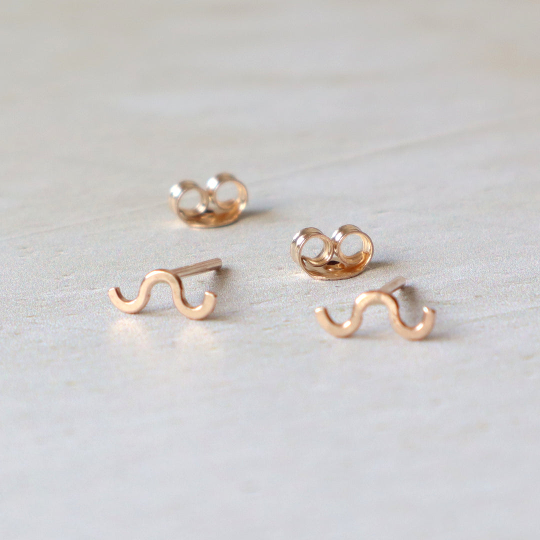 Set of gold filled squiggle stud earrings on a light gray background